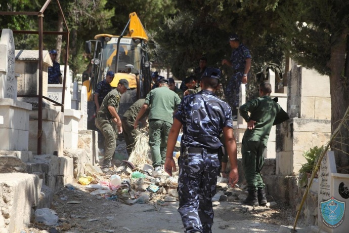 الشرطة والامن الوطني يقومان بتنظيف المقابر في نابلس بالتعاون مع البلدية .